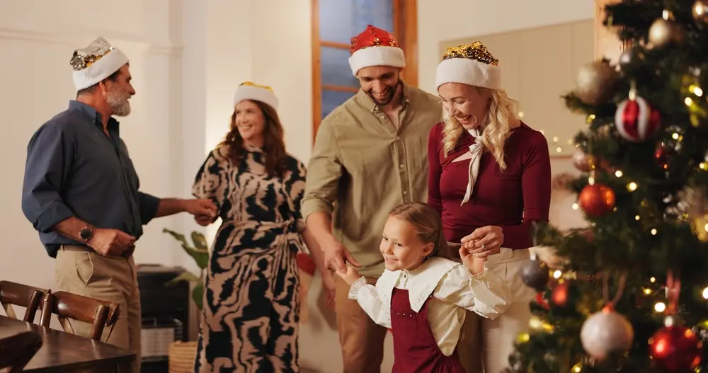 Famille réunie pour Noël, portant des bonnets de fête et tenant des cadeaux à offrir