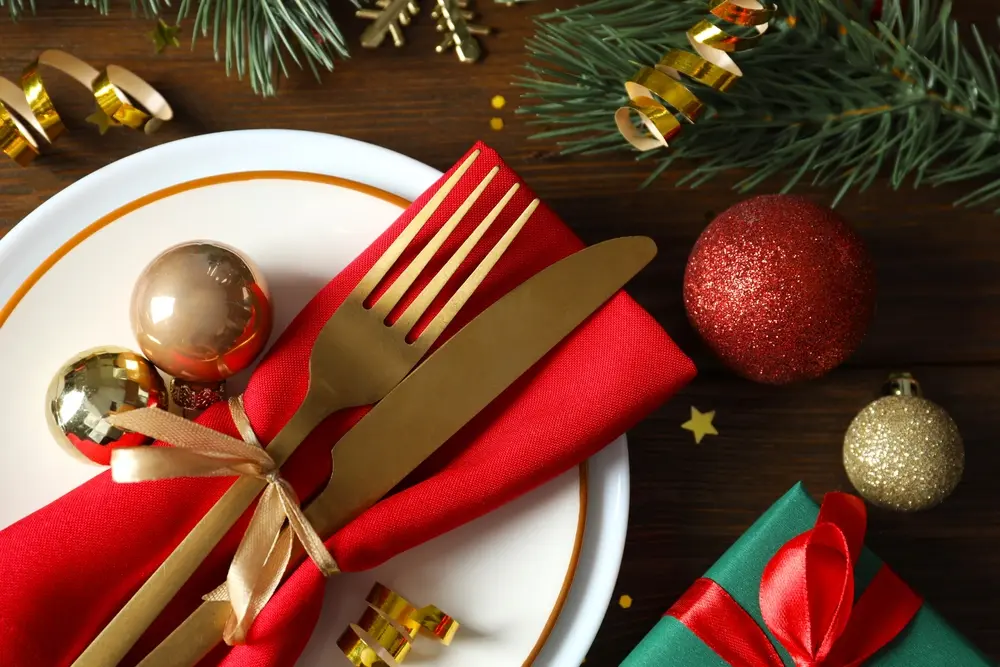 Tavola imbandita per Natale con tovagliolo rosso e posate dorate, per un regalo gastronomico
