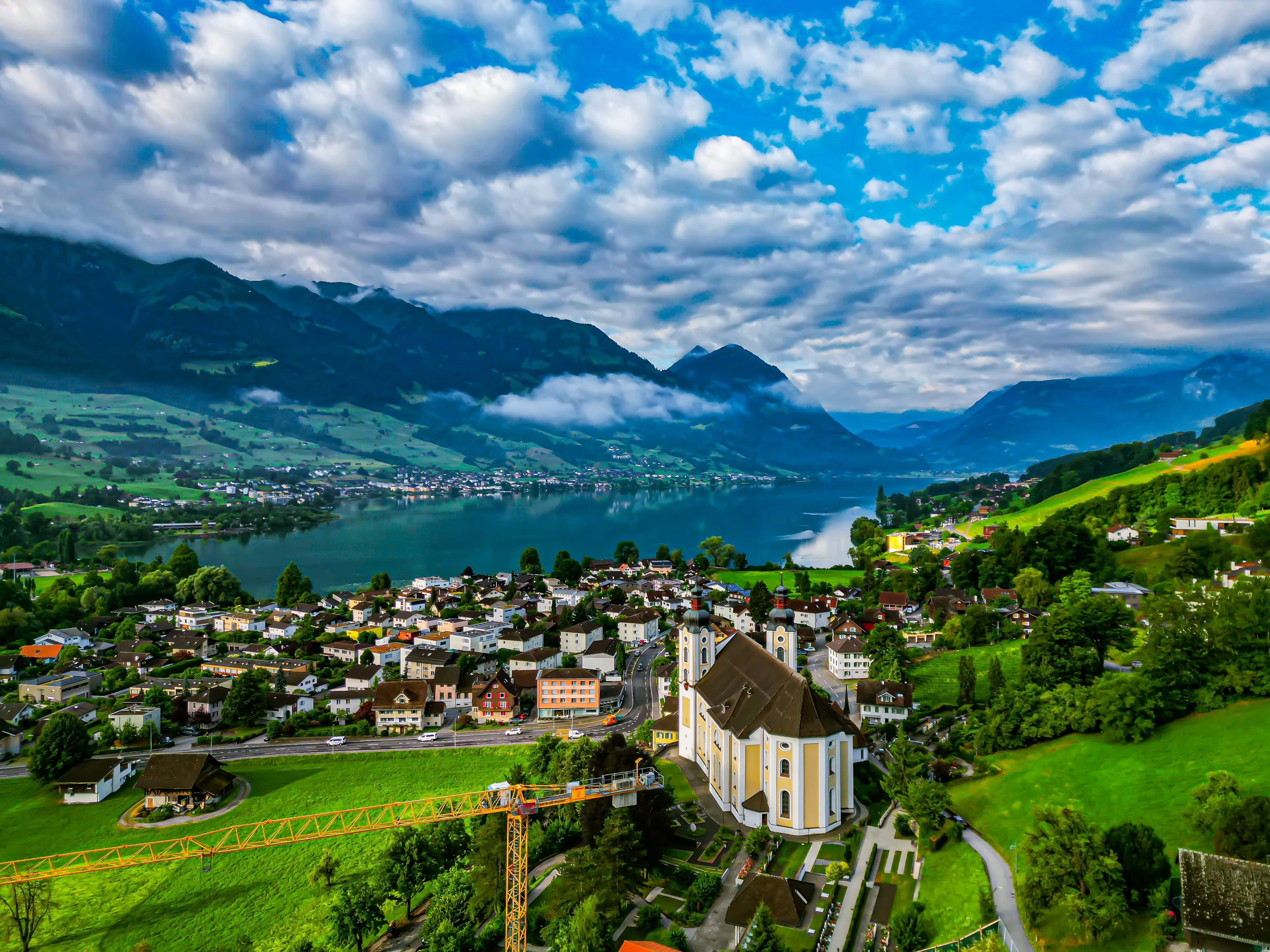 Vue Aérienne de la périphérie de Lucerne, Suisse, avec un quartier paisible avec des maisons confortables près d'un lac calme, entouré de champs verdoyants, de douces collines et les majestueuses Alpes suisses 